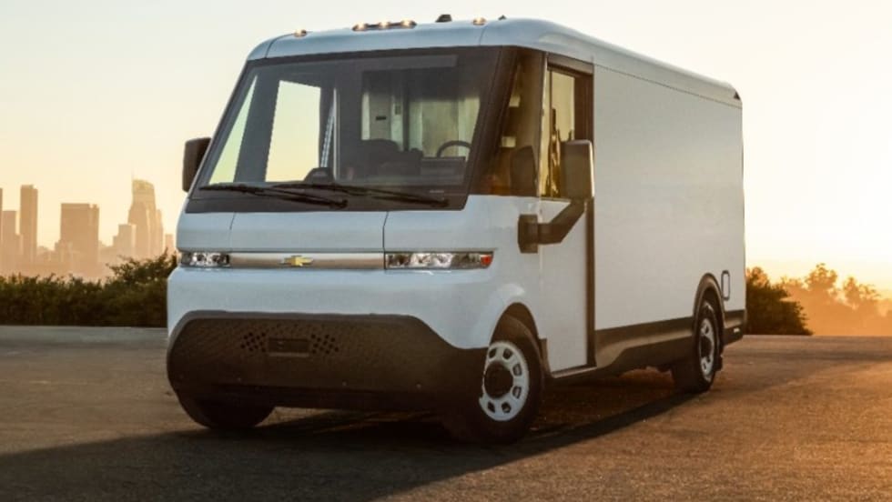 White electric delivery van parked in front of a city skyline.