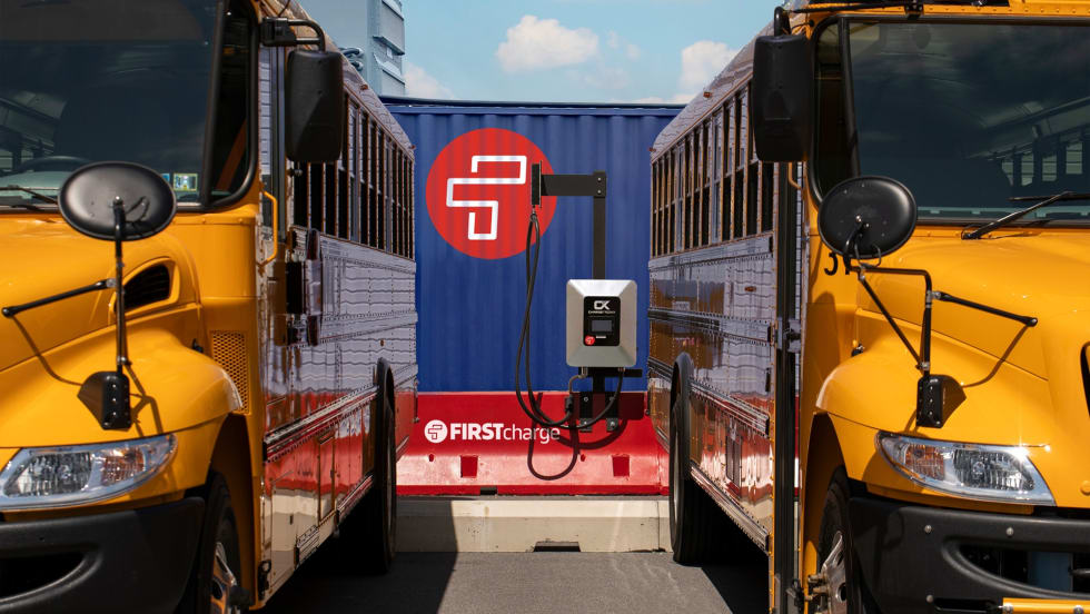 two school buses plugged into a charging station