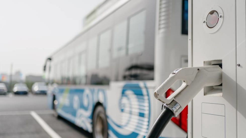 A bus parked at an electric vehicle charging station.