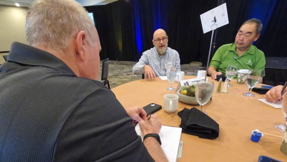 Men discussing topic around a table.