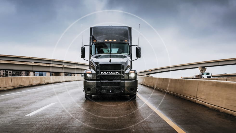 Black Mack Truck driving toward camera on highway.