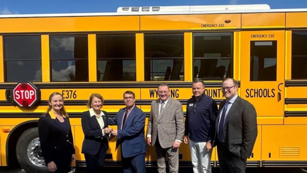 A GreenPower school bus with administrators in front of it.