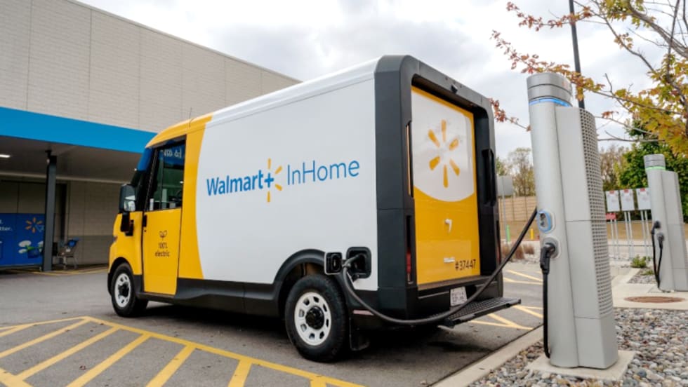 A Walmart BrightDrop battery-electric van is shown at a charging station.