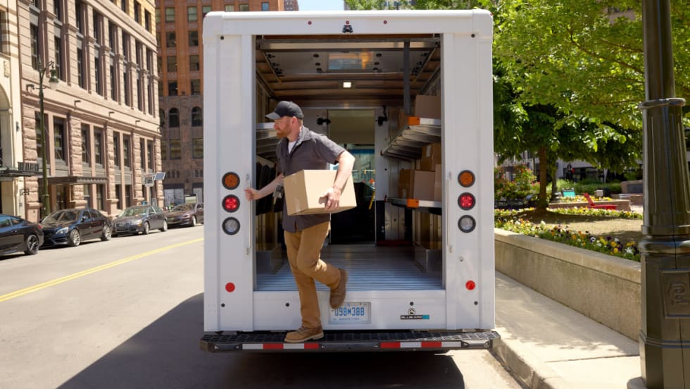 Package delivery person exits the rear of a step van.
