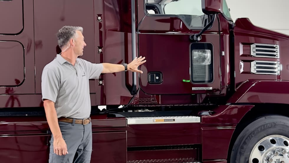 man standing in front of a Mack truck talking about it