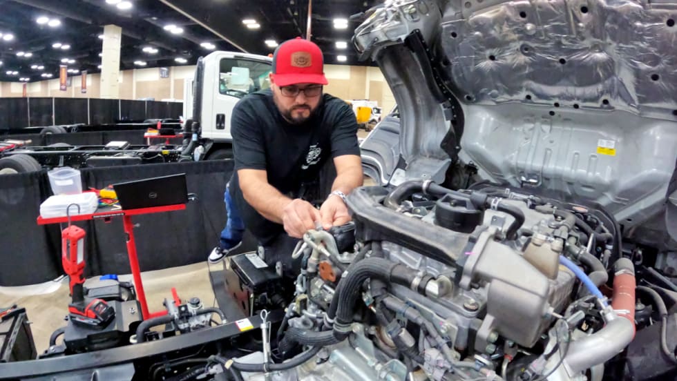 Truck technician works on the engine of a truck.