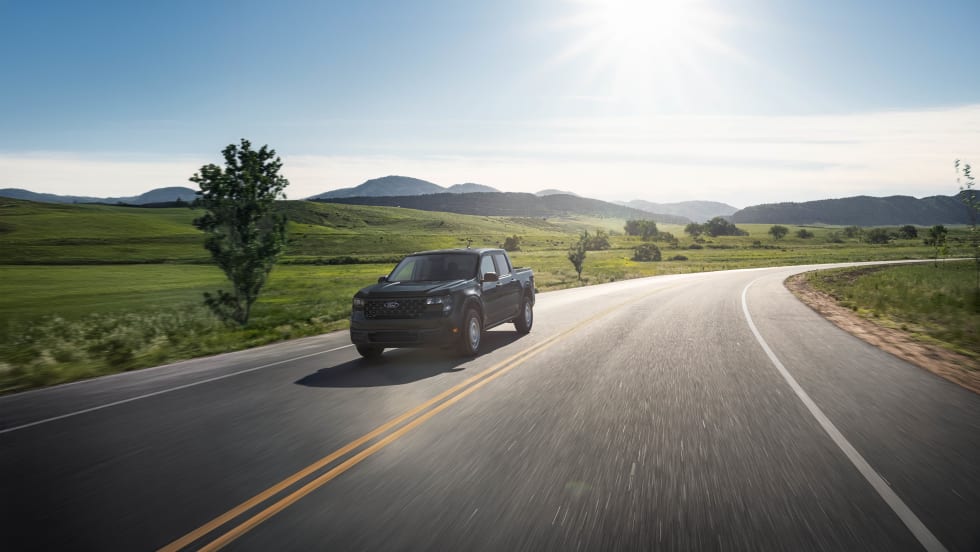 A black Ford Maverick XL is shown driving down a rural road.