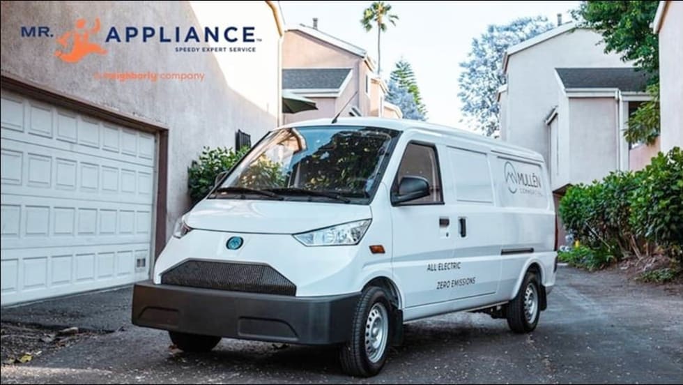White electric van parked outside a home.