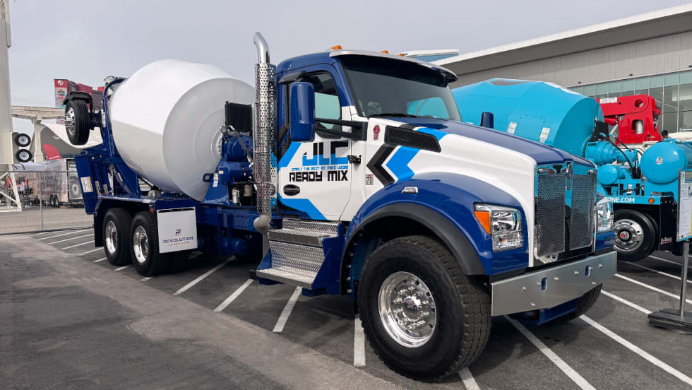 Photo of a concrete truck parked, blue and white cab, white mixer.