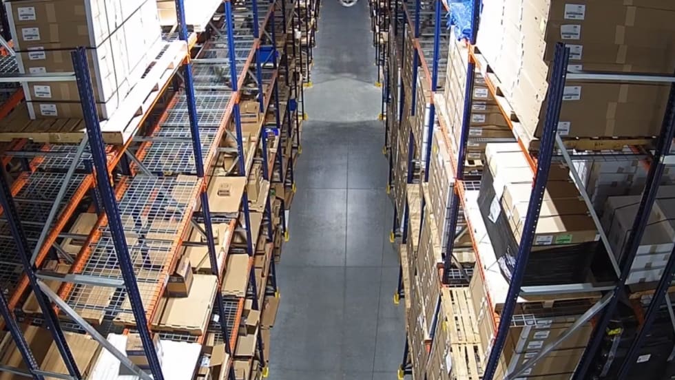 Warehouse aisle with pallet racking filled with boxed inventory at a distribution center.