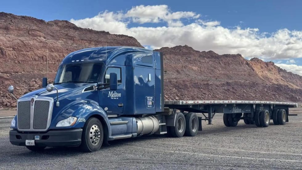 Blue heavy-duty tractor pulling a flatbed trailer