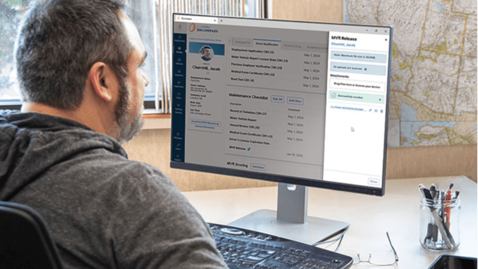 Man looks at a computer screen with reports on it. 
