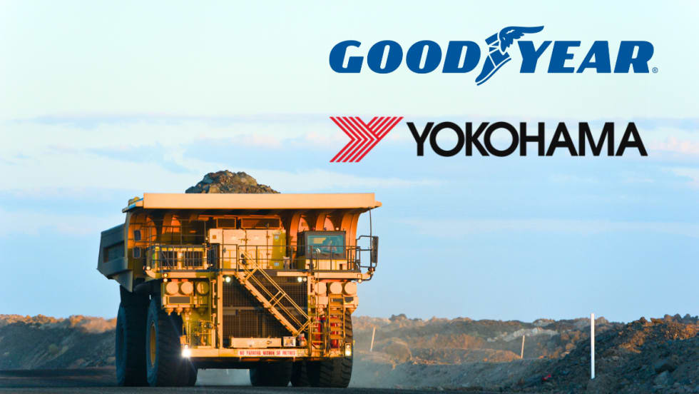 Large mining dump truck driving and logos against a blue sky for Goodyear and Yokohama.