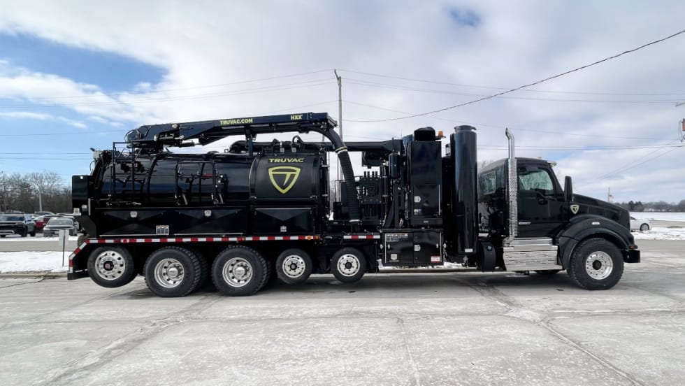 Large black vacuum truck with six axles.