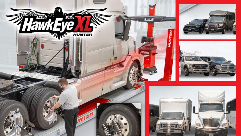 Tire technician working on a large truck tire with truck positioned on a wheel alignment system.