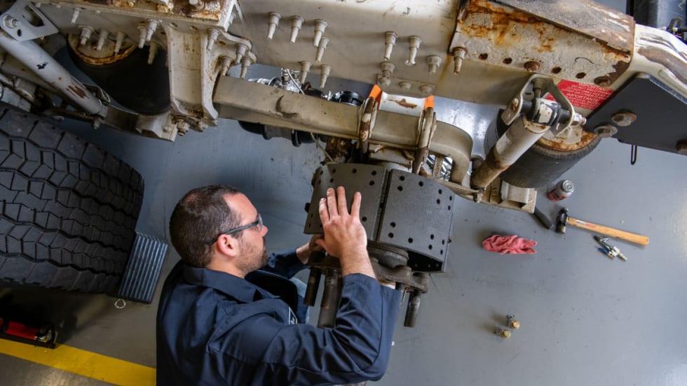 Male maintenance technician working on truck brakes.