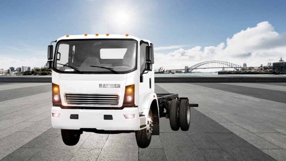 White low-cab forward truck against a parking lot scene. 