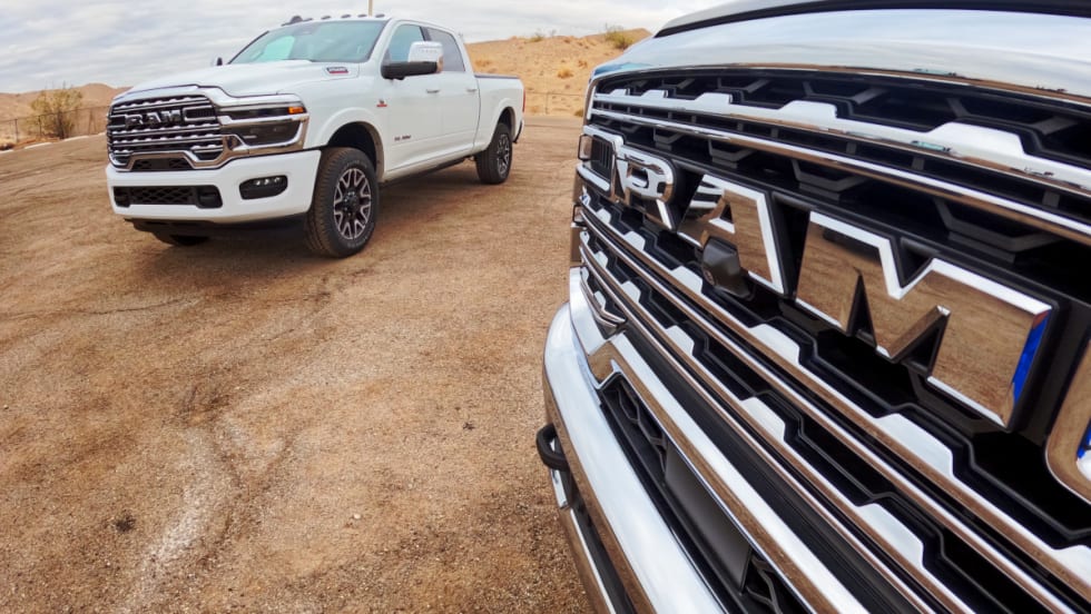 Close photo of front grille of a Ram truck, with another truck in the background