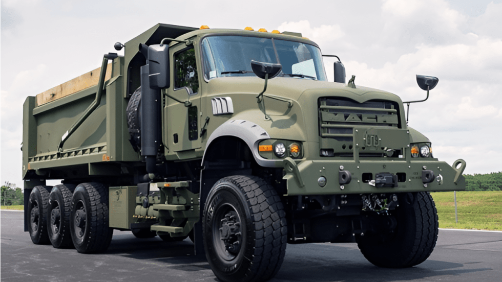 Mack military dump truck view from a low angle against a blue sky.