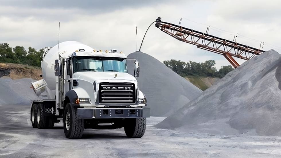 Mack concrete truck in a work setting surrounded by aggregate.