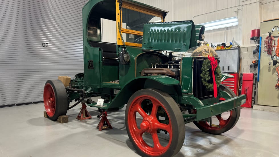 Antique Mack Truck from 1925 with green paint and red wheels.