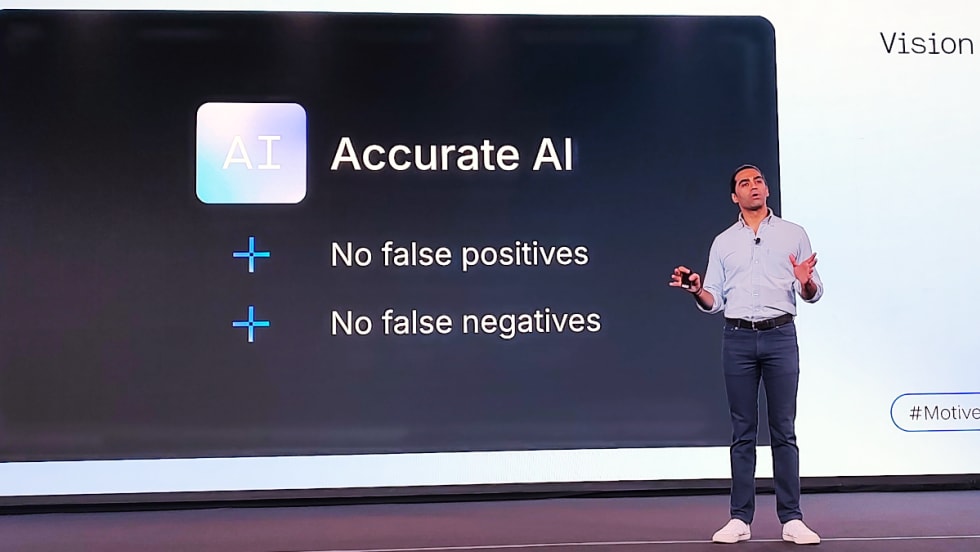Business leader lecturing on stage in front of a protected graphic about AI.