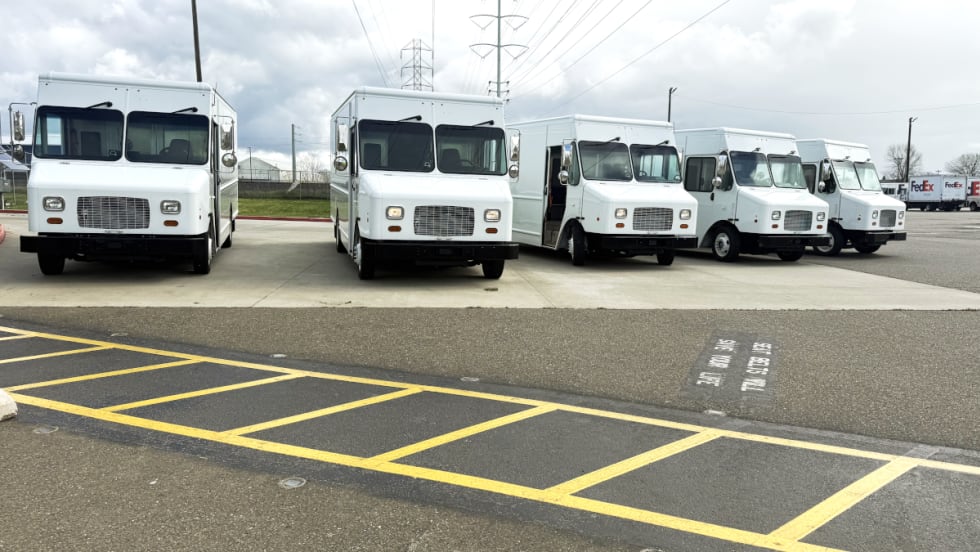 Five white step vans parked facing the camera.