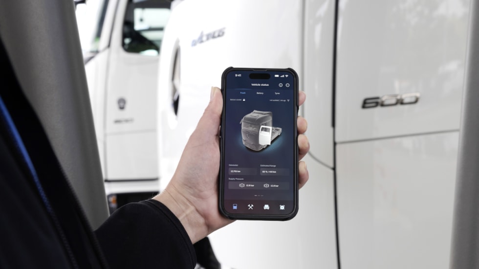 Closeup of a Mercedes-Benz app on a phone with part of a truck in the background.