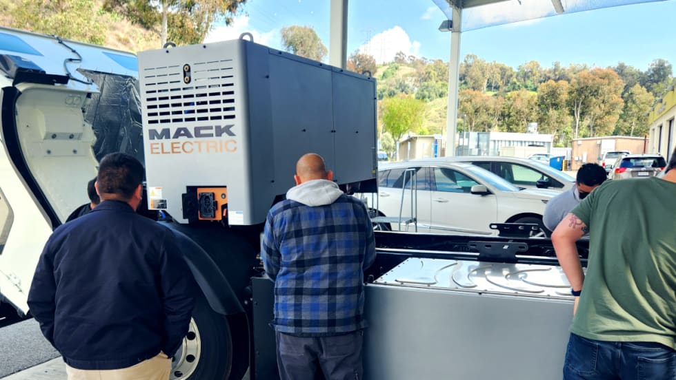 Students look over a Mack LR Electric chassis.