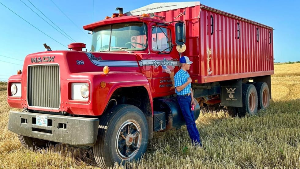 A red Mack Truck farm truck in a field.