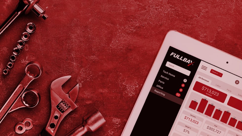 Tablet screen displaying Fullbay's repair shop management dashboard with revenue data, surrounded by hand tools on a red textured surface.