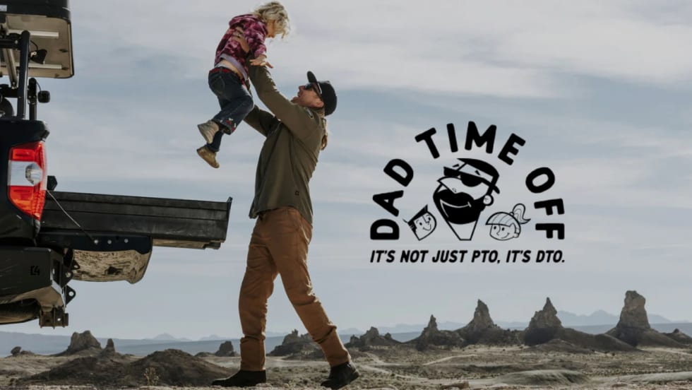 A dad lifts his child near a truck bed in a desert setting with the DECKED Dad Time Off logo and slogan: “It’s not just PTO, it’s DTO.”