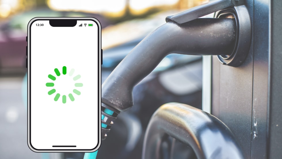 A smartphone with a loading icon displayed on the screen appears in front of an electric vehicle charging station, symbolizing delays or connectivity issues with EV mobile apps.