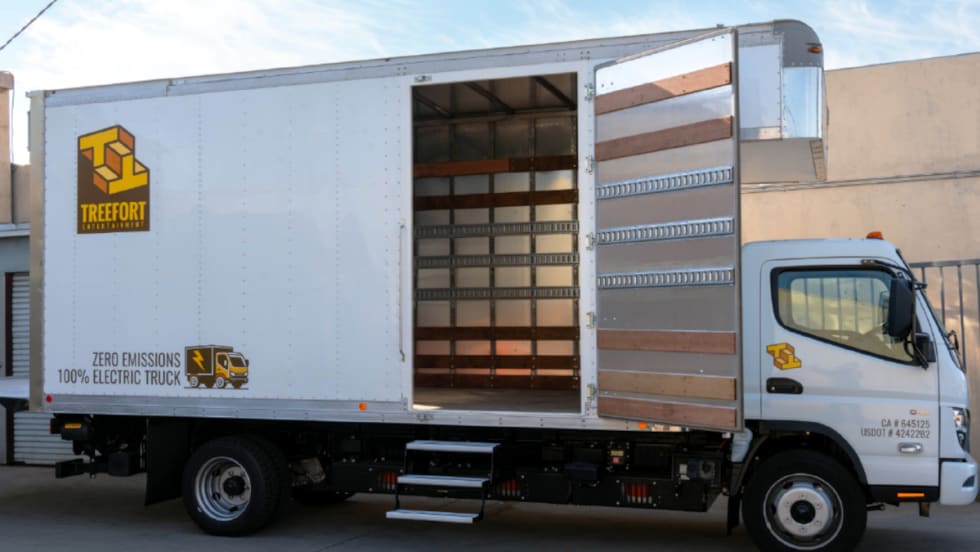 Medium-duty battery-electric box truck parked with side door open.