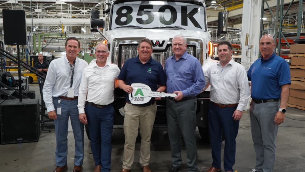 Six men stand in front of a Western Star truck marked “850K” at DTNA’s Cleveland plant, holding a ceremonial key for the 850,000th truck delivered to Alamo Group for snow and ice operations.