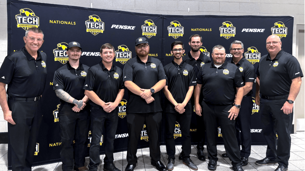 Group of men, award winners in a competition, dressed in all black standing on a stage to receive awards.