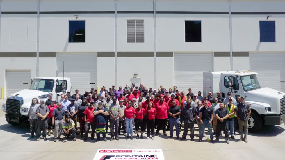 Group photos of people standing in front of two commercial trucks parked in front of a building.