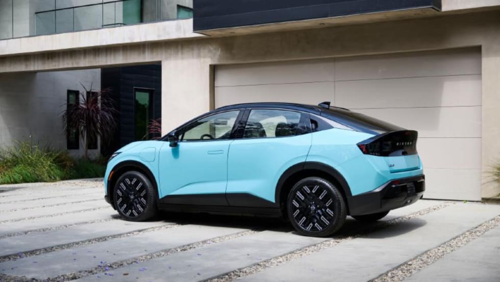 Light blue Nissan EV parked in front of a modern home garage, highlighting residential charging compatibility.