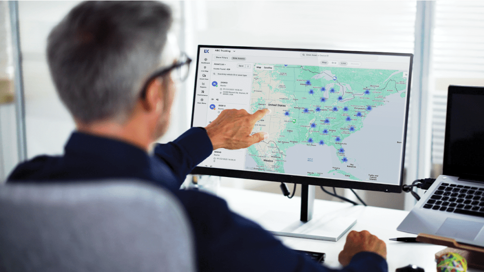 Man pointing to a map and data points on a computer screen.