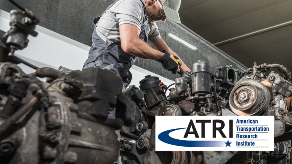 A diesel technician works on a large engine in a repair shop, wearing gloves, safety glasses, and a cap, with the ATRI (American Transportation Research Institute) logo overlayed in the foreground.