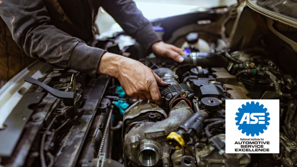 Mechanic working on an engine under the hood of a car with the ASE (National Institute for Automotive Service Excellence) logo in the foreground.