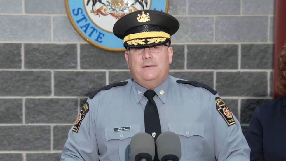 Pennsylvania State Police officer speaking at podium with official seal behind