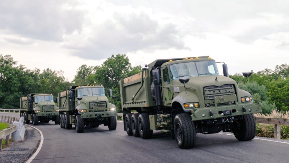Three military dump trucks driving on a test track.