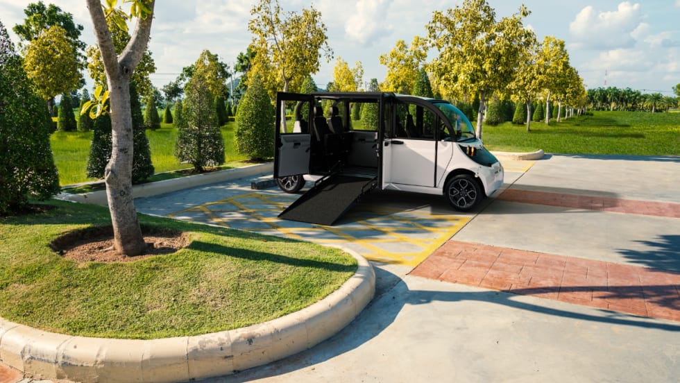 White GEM Wheelchair Accessible Vehicle parked in a handicap space with ramp extended for wheelchair access.