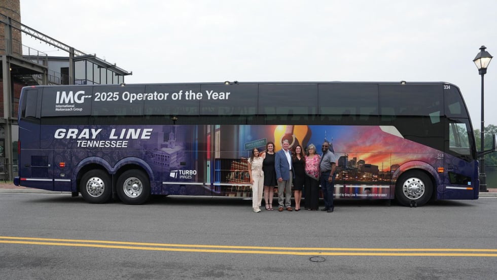 Gray Line Tennessee team poses in front of a custom motorcoach wrap celebrating the company’s recognition as 2025 IMG Operator of the Year.