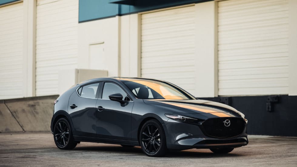2026 Mazda3 hatchback in gray parked outside an industrial building.
