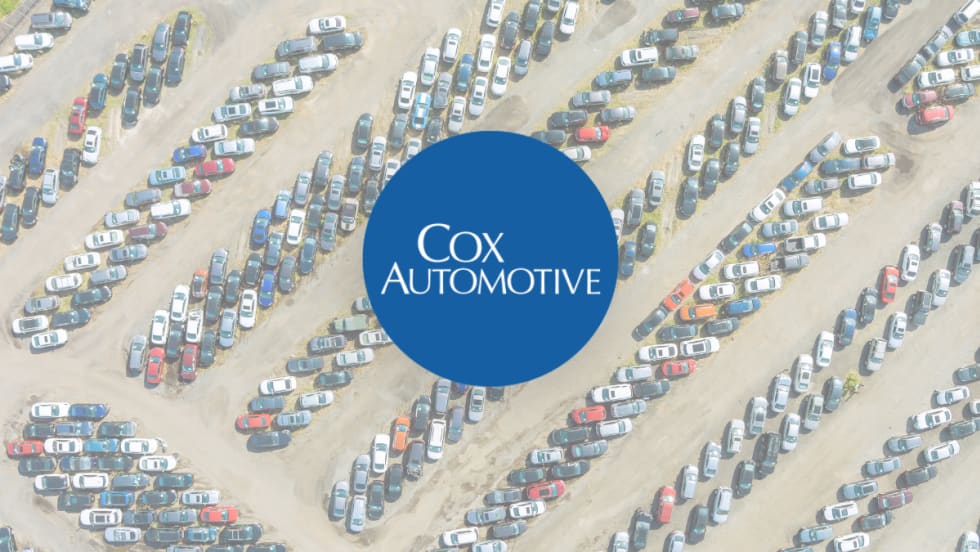 Cox Automotive logo overlay on aerial view of large auto auction lot filled with rows of parked vehicles.