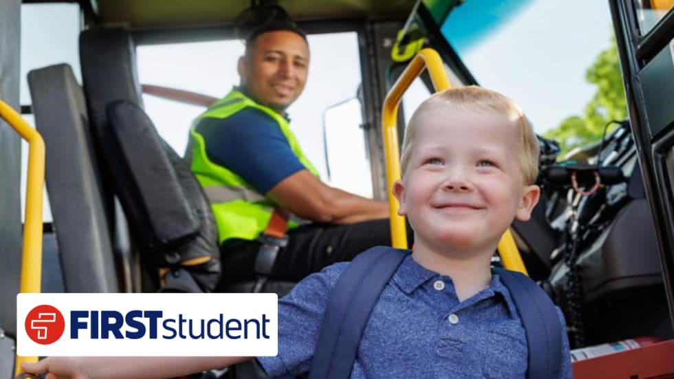 Young student boarding a school bus with driver in background, representing First Student’s new transportation partnership with Seneca Valley School District.