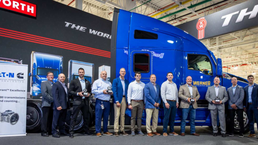 Group of Eaton Cummins and Werner Enterprises representatives standing in front of a blue Kenworth T680, commemorating the 500,000th Endurant transmission milestone.