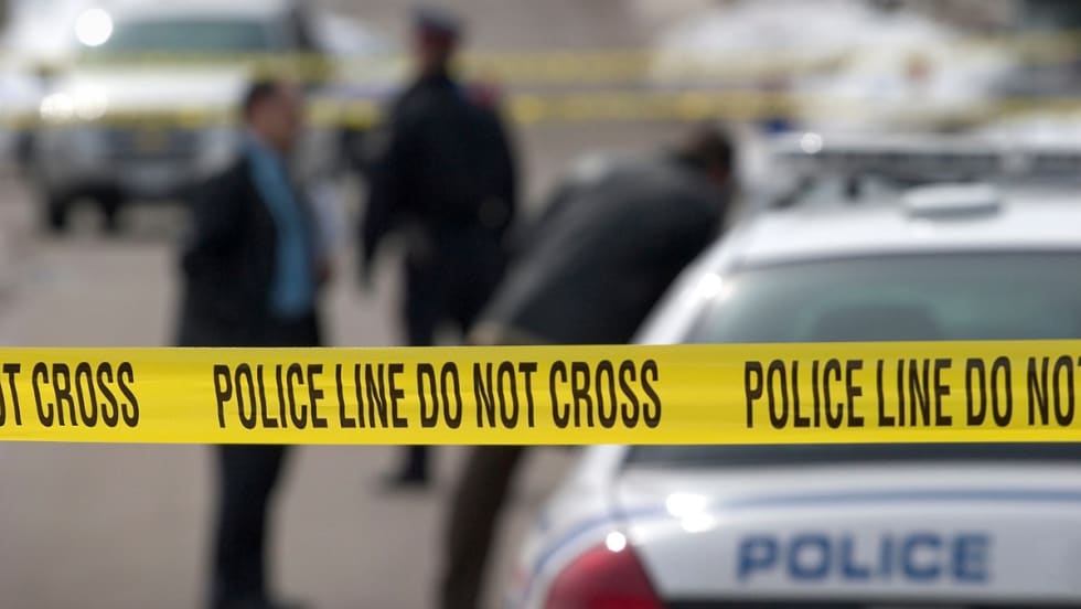 Yellow police tape cordoning off a crime scene with police vehicle